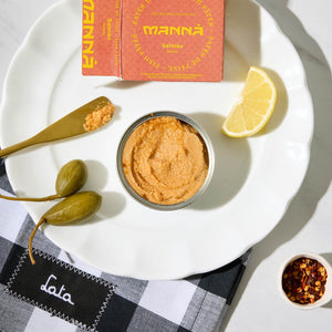 An opened tin of Manná Salmon Pate served with capers and lemon