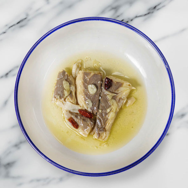 Alalunga Seabass in Garlic Sauce served beautifully in the center of a white plate with blue rim