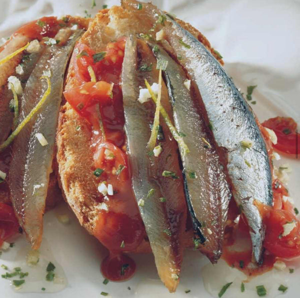 Rosalita Smoked Anchovies in Olive Oil served on toasted bread with fresh tomatoes