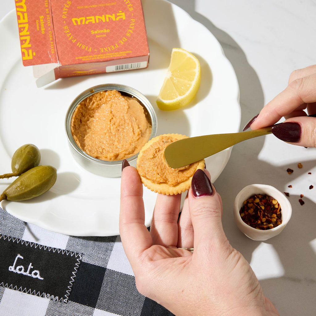 A person spreading a helping of Manná Salmon pate on a cracker