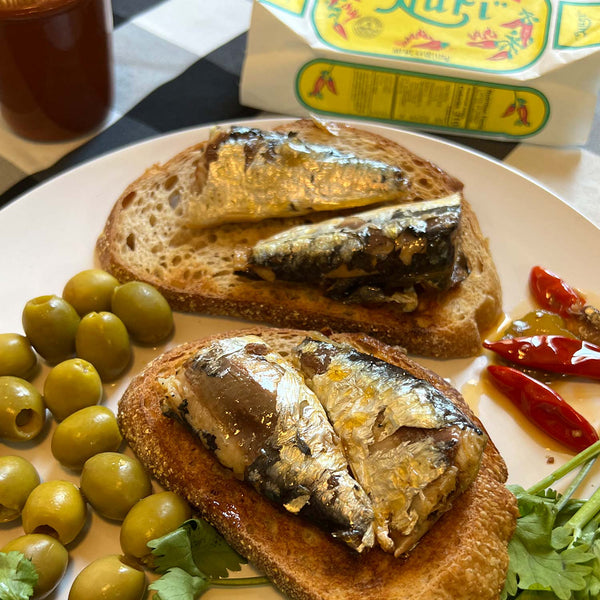 Nuri Extra Spiced Sardines in Olive Oil on bread, served with olives and peppers
